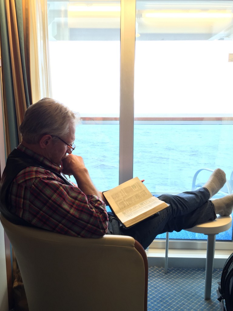 I'm reading my Bible in our stateroom with the balcony and a view of the ocean in the background.