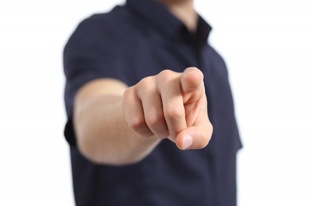 Close up of a man hand pointing at camera on a white background